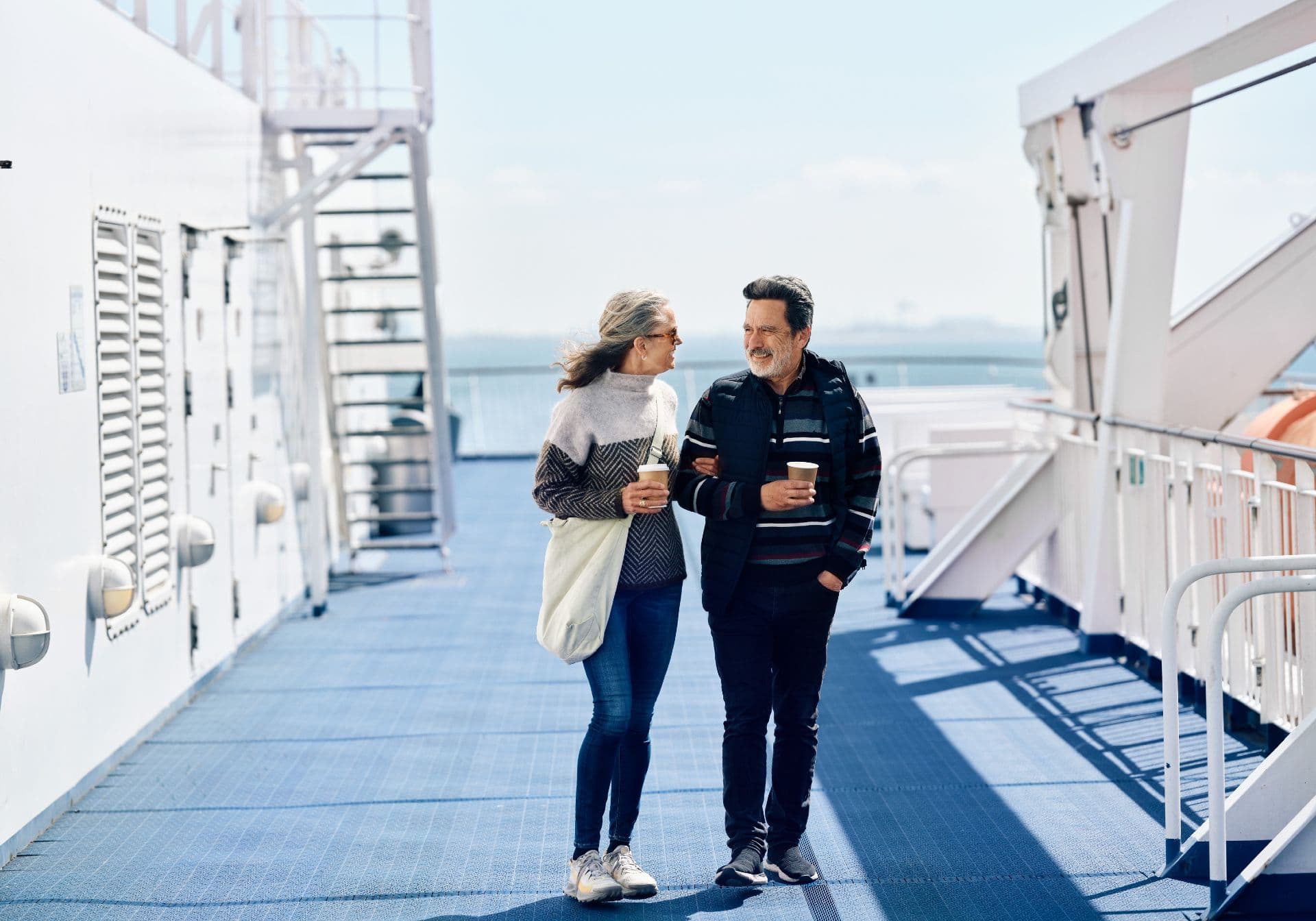 Couple with coffee in their hands on the ferry deck